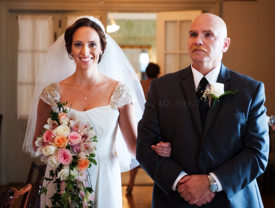 bride smiles as she and her dad walk down the aisle on her wedding day