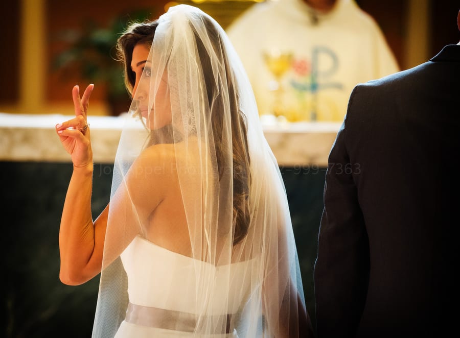 a bride gives the sign of peace during a catholic mass near Pittsburgh Pennsylvania