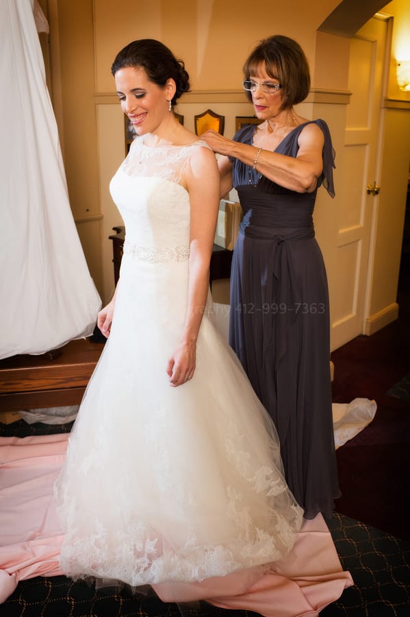 A bride's mother helps her with her wedding dress