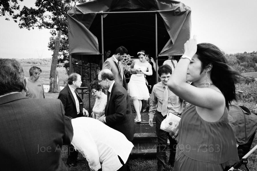 a bride and groom arrive at their wedding ceremony site in a covered hay wagon outdoor wedding in pittsburgh
