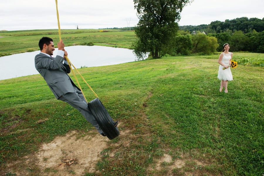 a groom swings on a tire swing as his bride laughs outdoor wedding in pittsburgh
