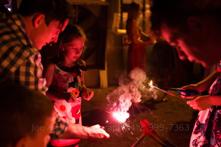 men help little kids light sparklers during a wedding reception outdoor wedding in pittsburgh