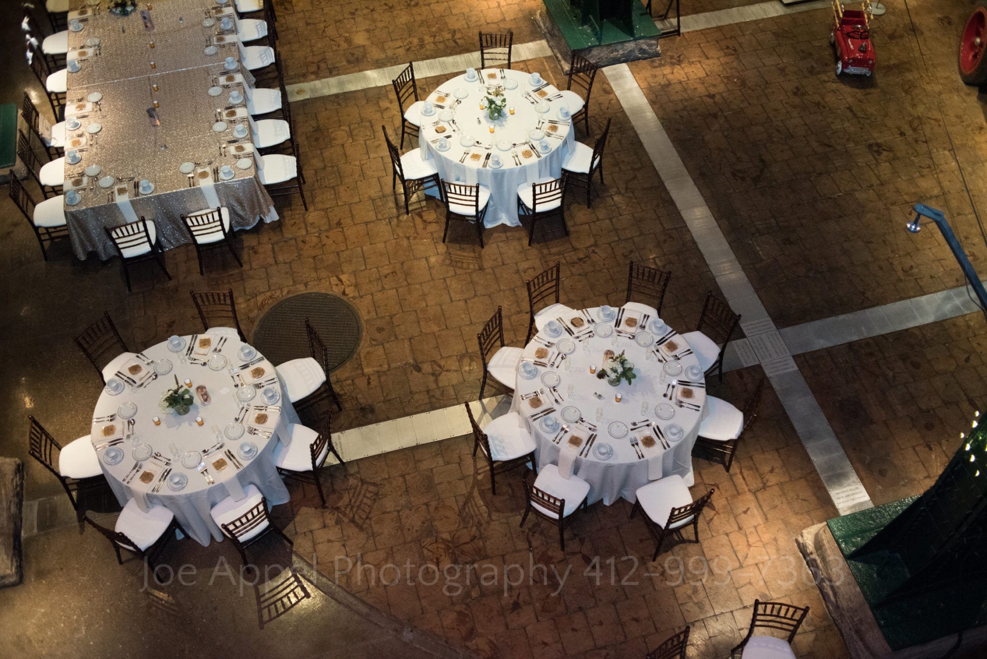 White table cloths cover tables of various shapes seen from above.