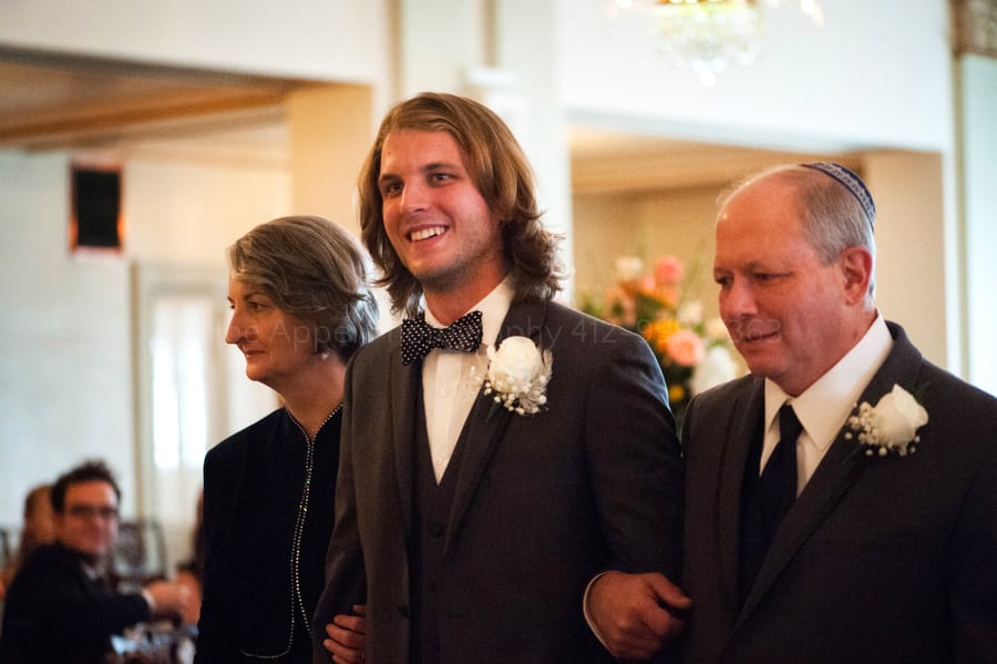 groom walks down the aisle with his parents in the Jewish tradition
