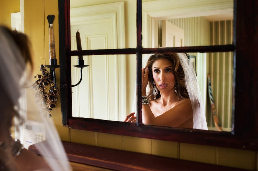 a bride fixes her hair in a mirror before her wedding near Pittsburgh. Wedding Photography at Lingrow Farm.