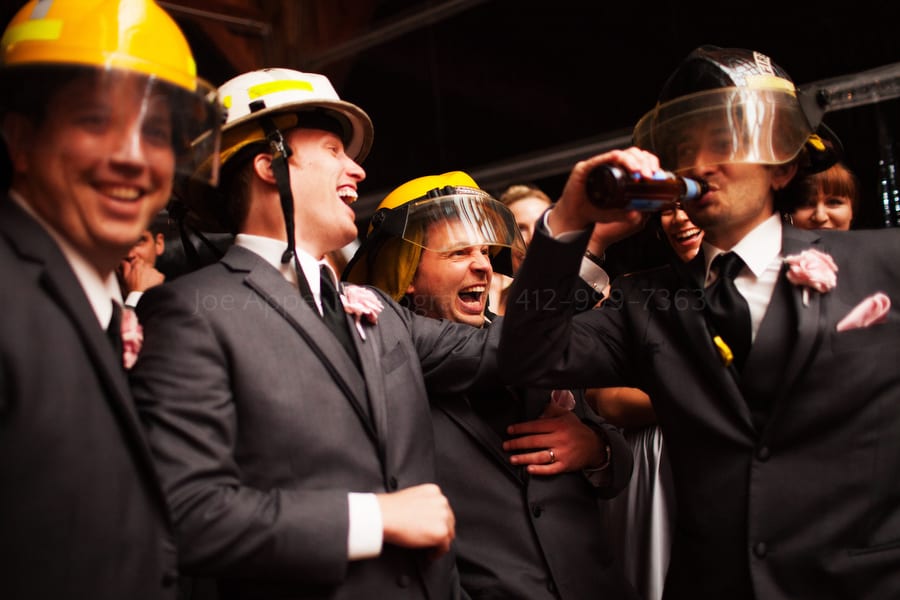 groomsmen wearing firefighting gear as they drink beer and laugh. Wedding Photography at Lingrow Farm.