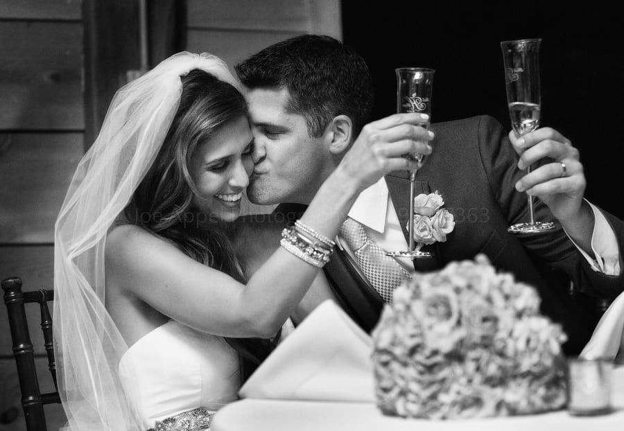 a groom kisses his bride during a champagne toast at their wedding reception. Wedding Photography at Lingrow Farm.