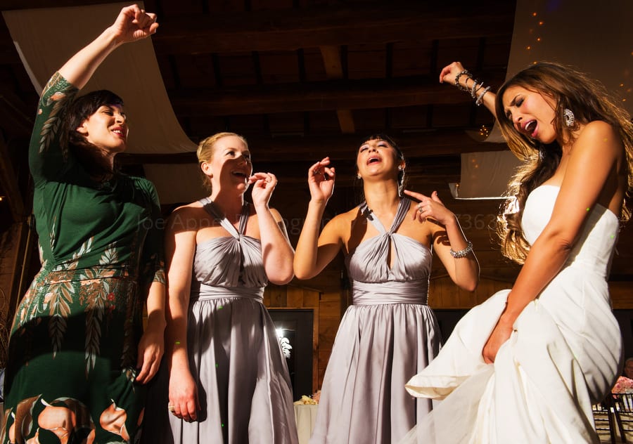 a bride and her friends sing and dance together at her wedding