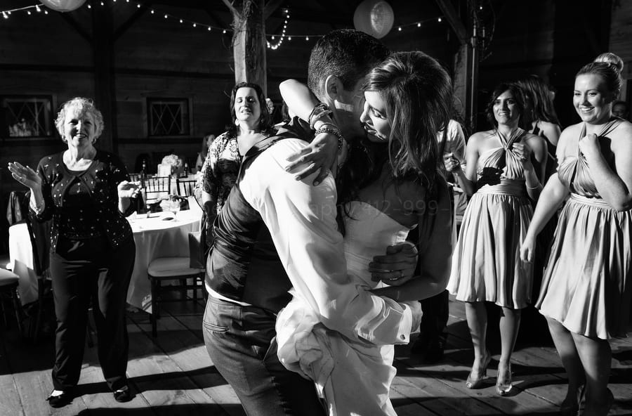 a bride and groom share an embrace on the dance floor of their wedding while the guests gather around them. Wedding Photography at Lingrow Farm.