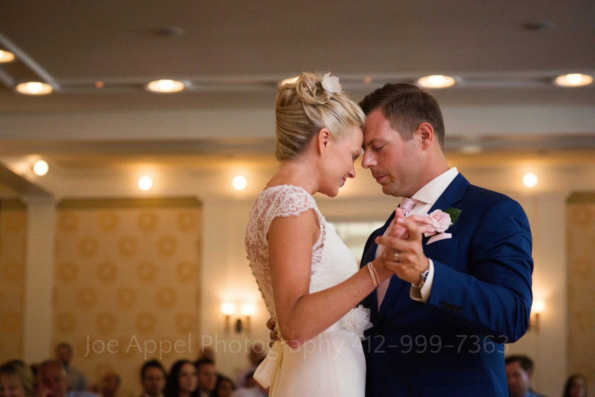 Bride and groom dance with their foreheads touching in a high ceilinged room during their Omni Bedford Springs Resort Wedding.