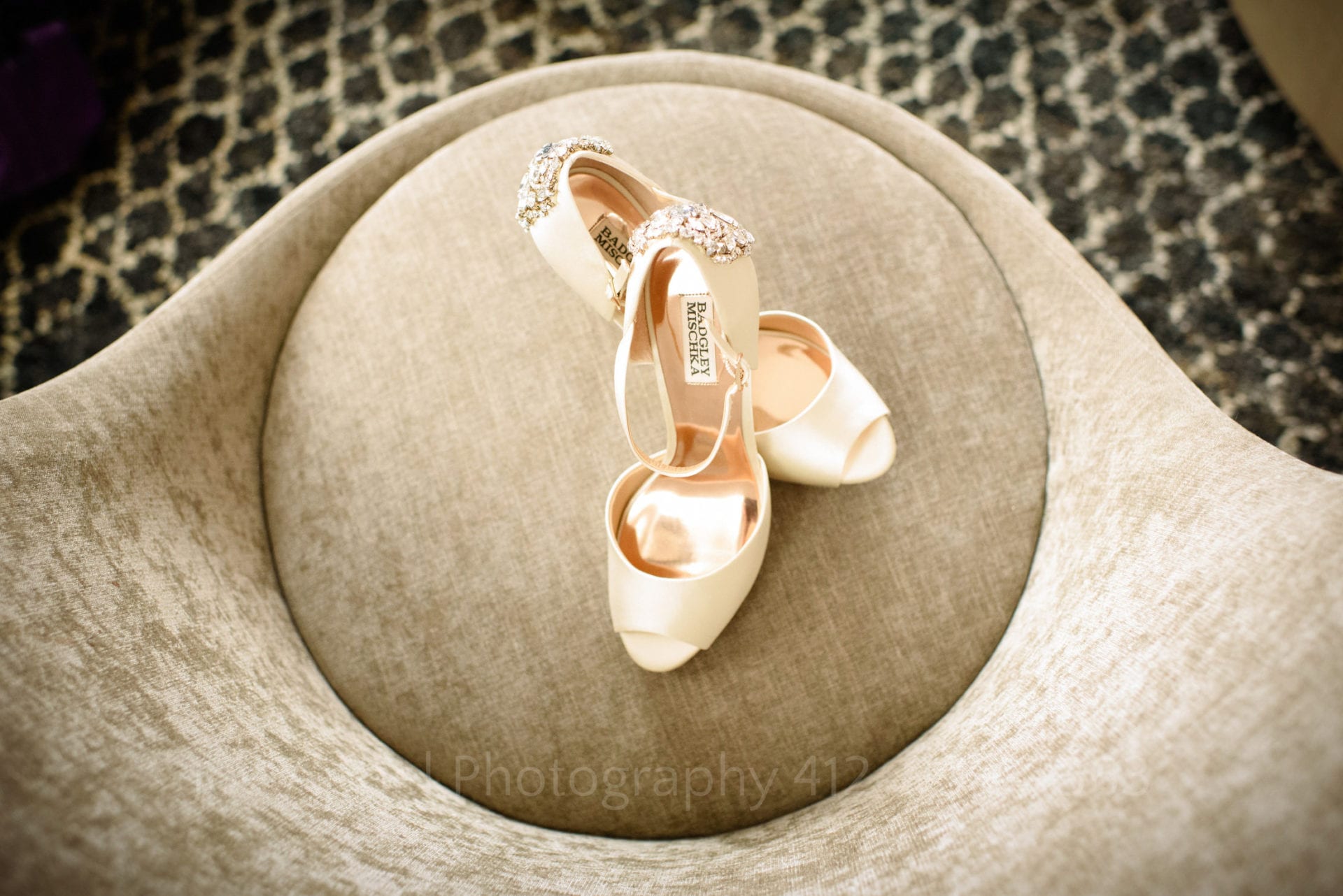 Badgley and Mischka open toed shoes seen from above while on a circular chair cushion.