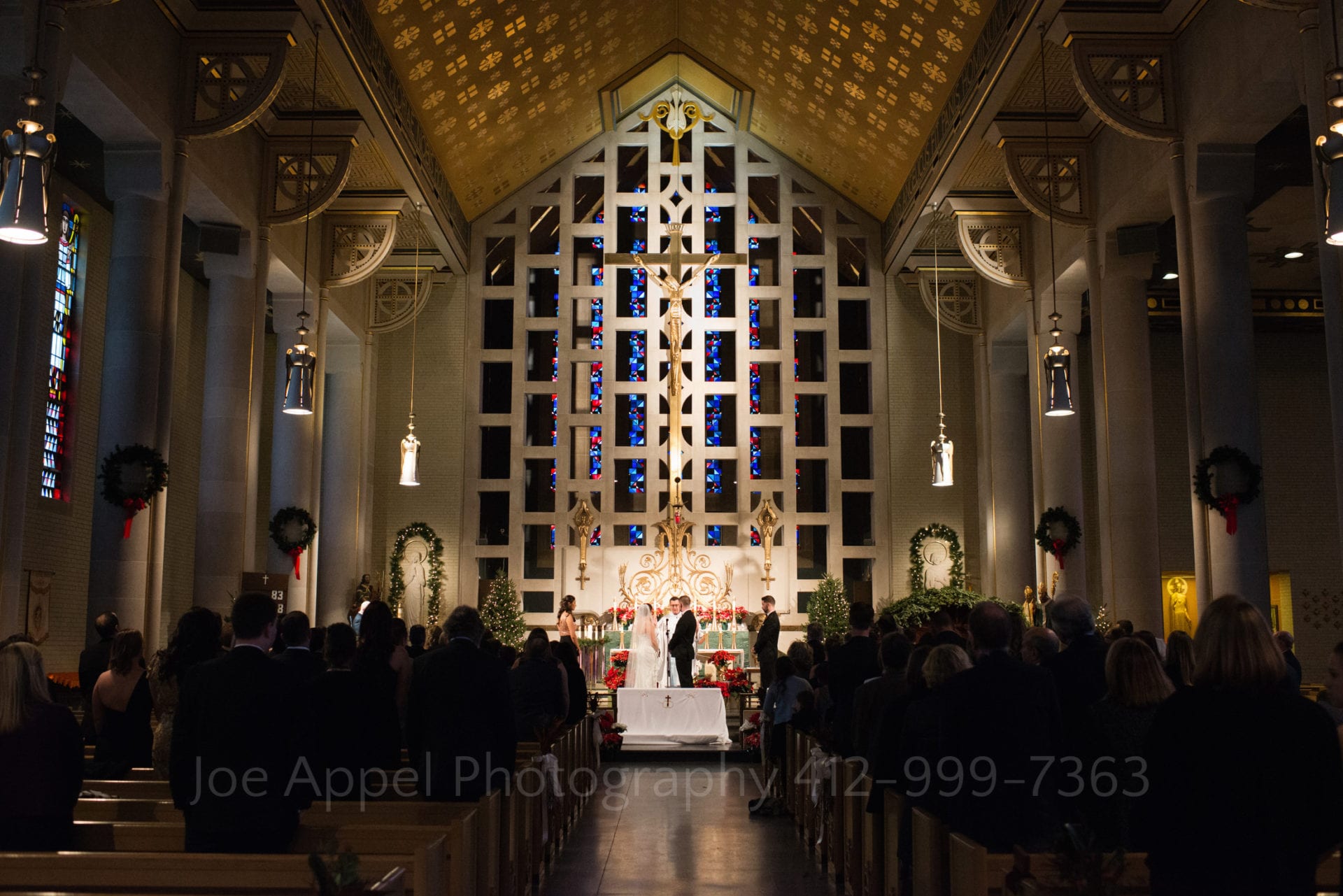 The interior of St. Raphael parish in Stanton Heights with a bride and groom standing in the center as they exchange vows.