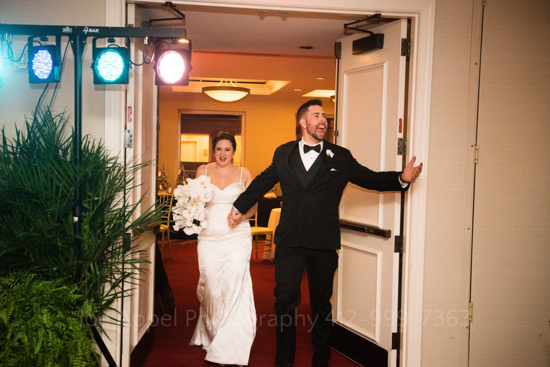 A groom holds his hand out and yells as he and the bride are introduced into their Renaissance Pittsburgh Hotel Wedding.