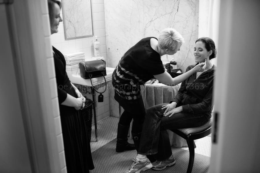 a bride has her makeup done in the ladie's locker room at Longue Vue Club before her wedding