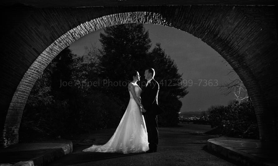 portrait of a bride and groom beneath one of the arches at Longue Vue Club
