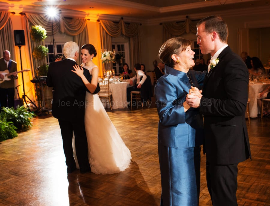 a groom dances with his mother while a bride dances with her father during their wedding
