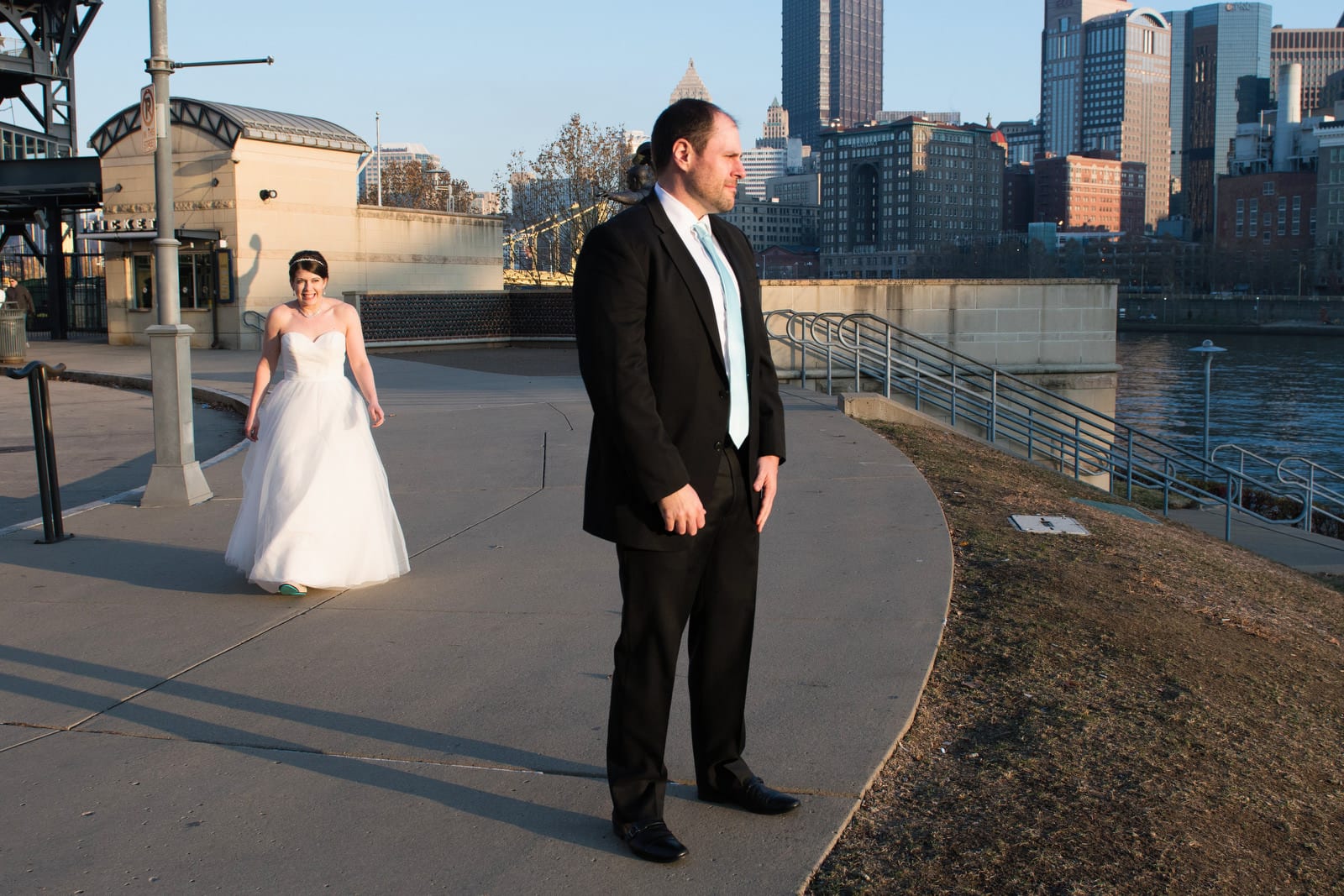 A bride approaches her groom as they have a first look on the north shore of the Allegheny River in Pittsburgh near PNC Park.