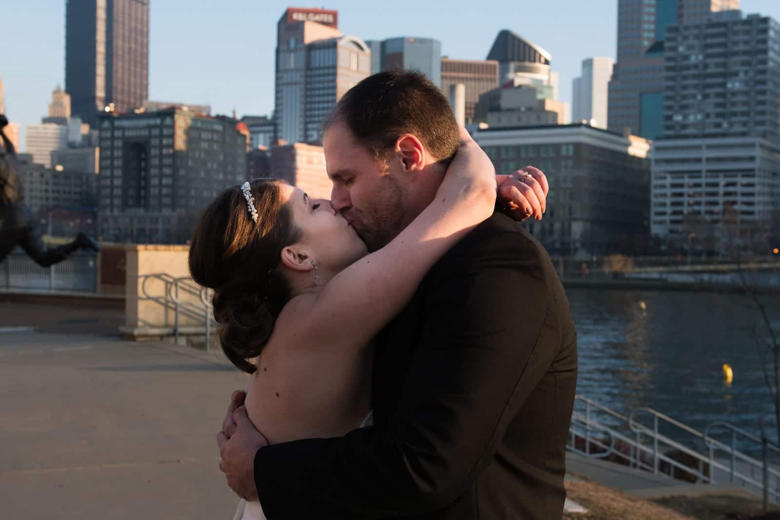A bride and groom kiss next to the Allegheny River in Pittsburgh.