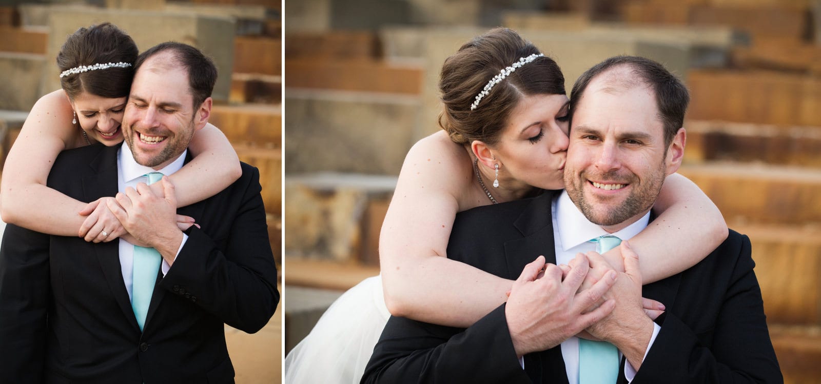 A bride holds her arms around the neck of her groom from behind and kisses his cheek.