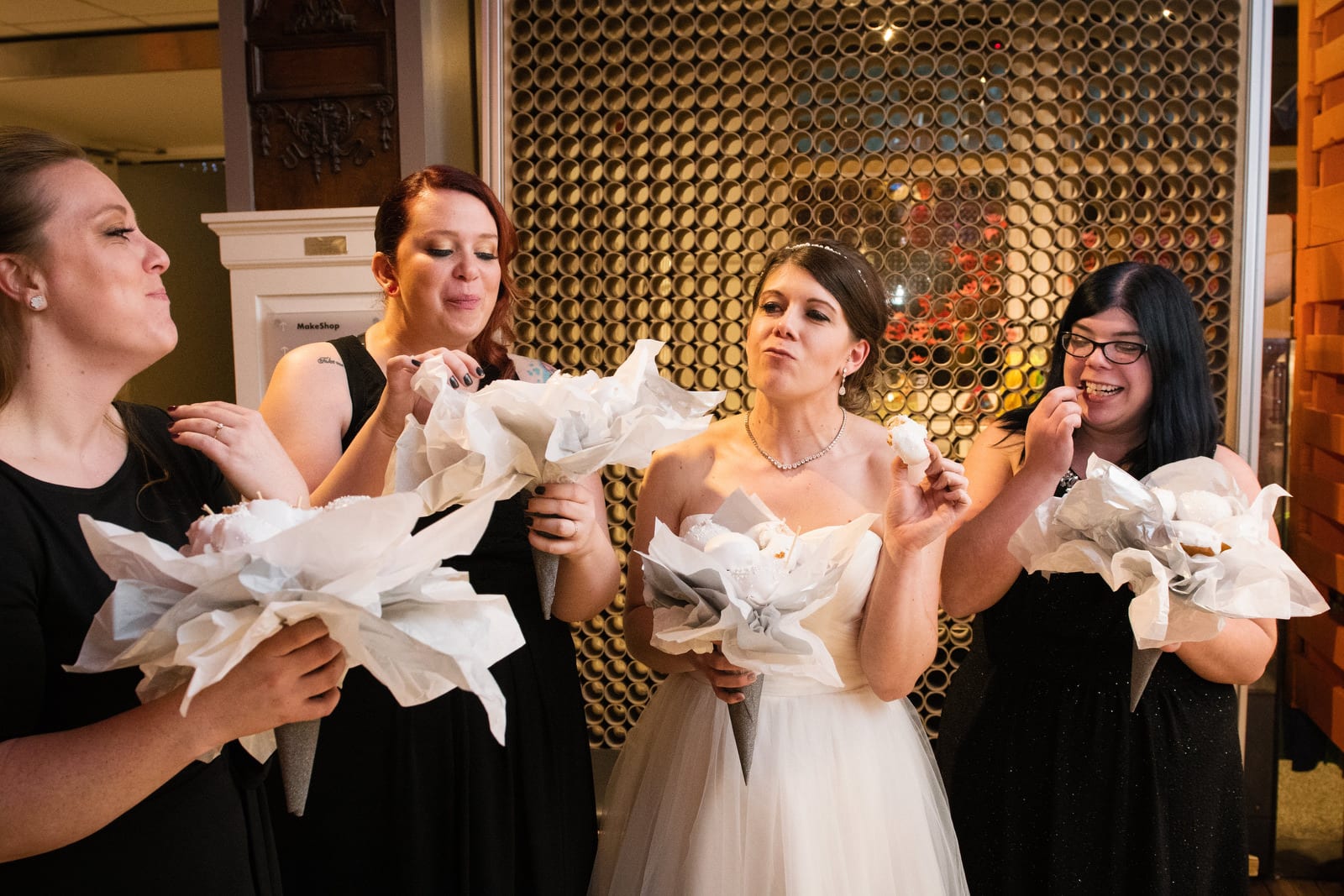 A bride and her bridesmaids munch the donuts from their bouquets.