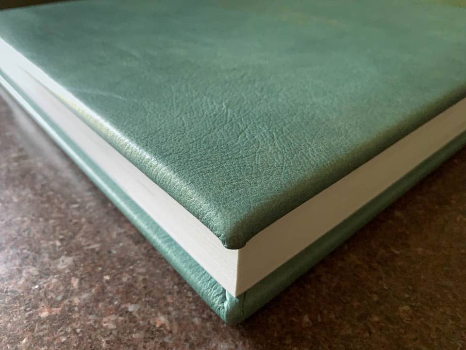 Detail photo of the sea blue/green leather cover of a 12x12 wedding album.