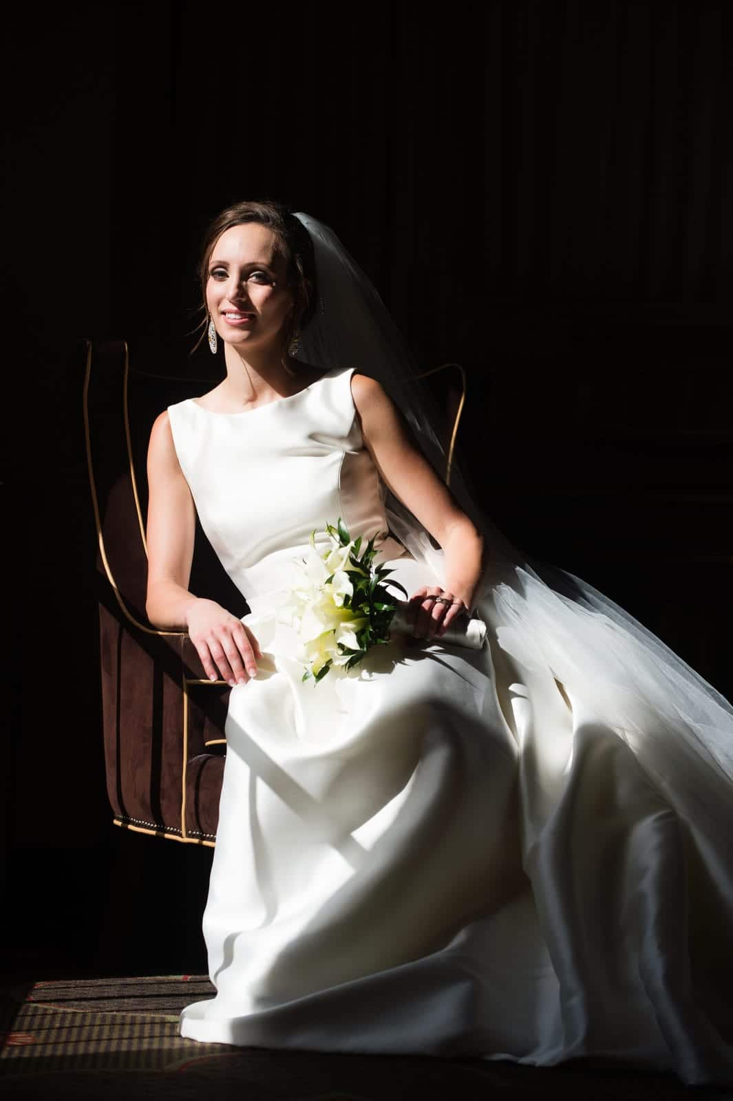 A bride reclines in a chair as the sunlight streams through a window in the lobby of the Omni William Penn hotel.