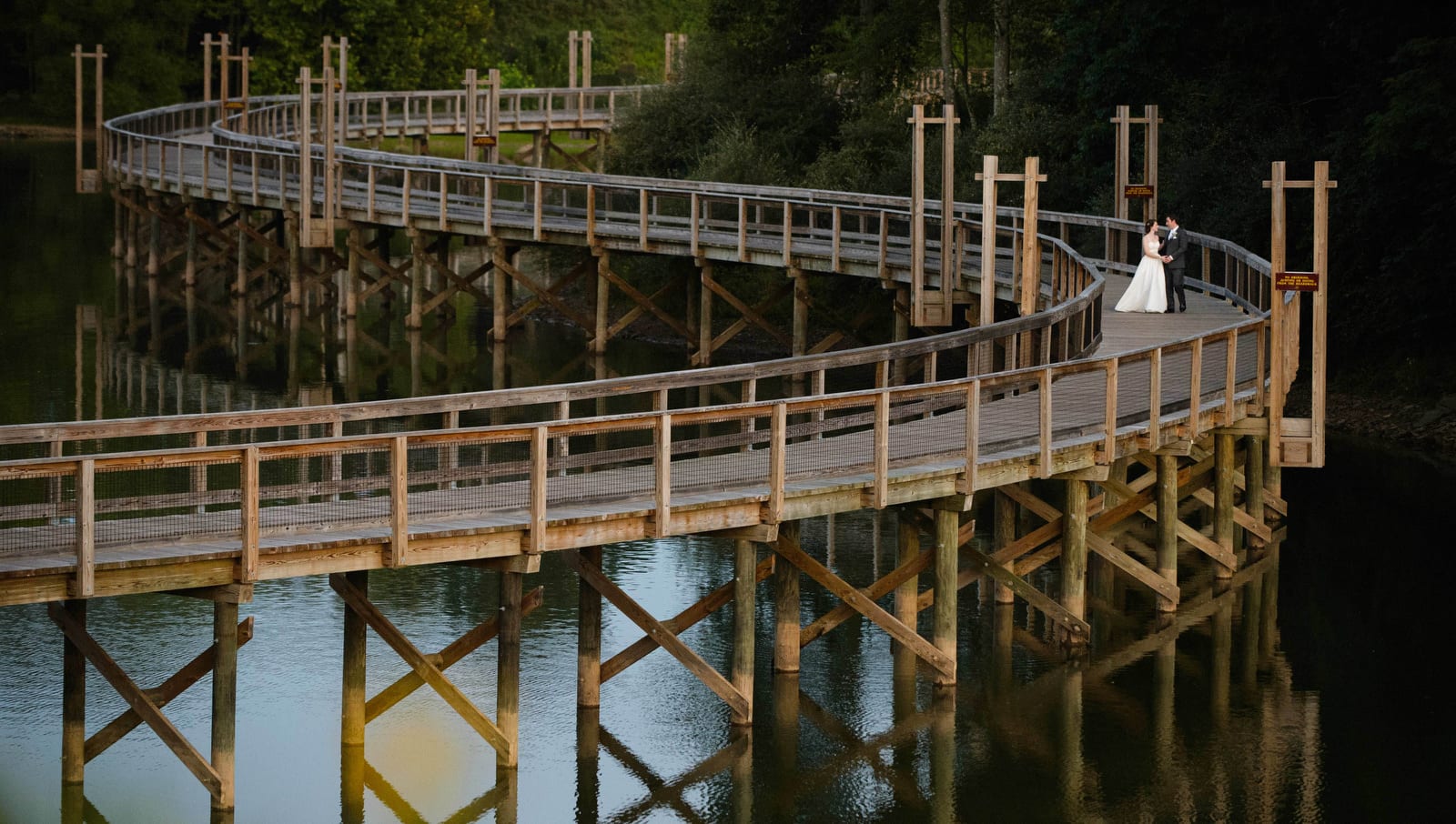 A bride and groom walk along an s-shaped pier after their wedding at Stonewall Resort in West Virginia.
