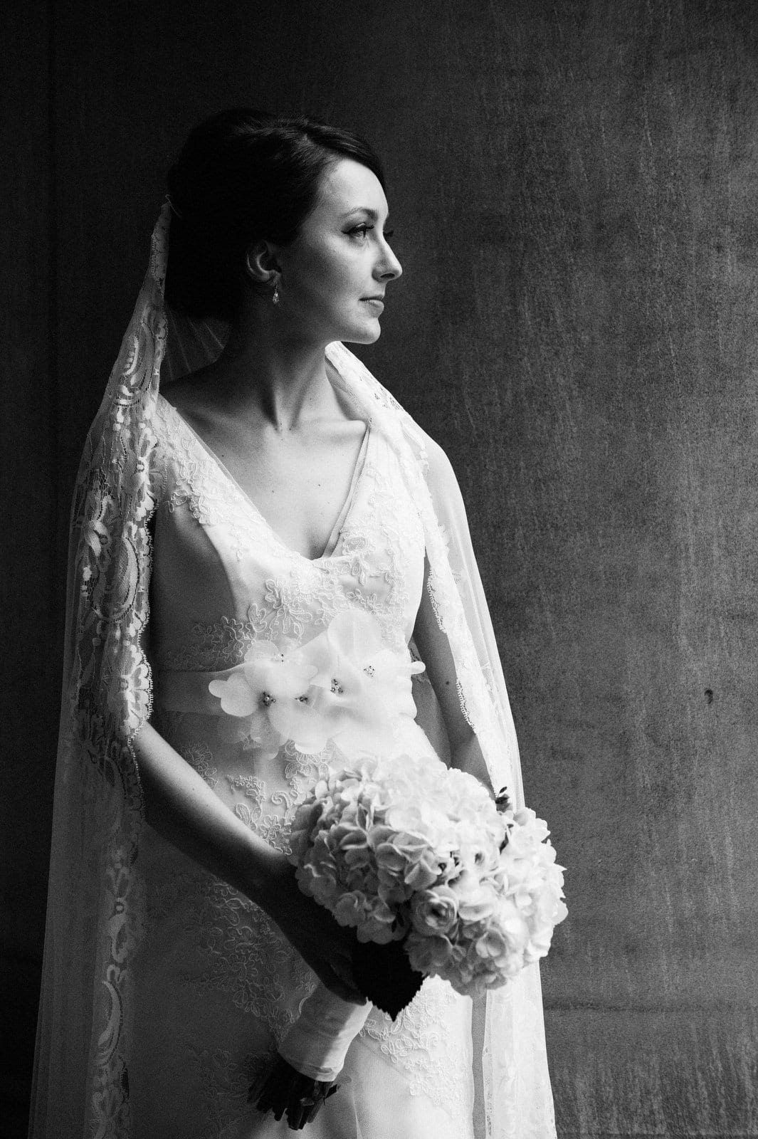 A bride in profile holds her bouquet with her cathedral veil over her shoulders at the Mellon Institute in Pittsburgh.