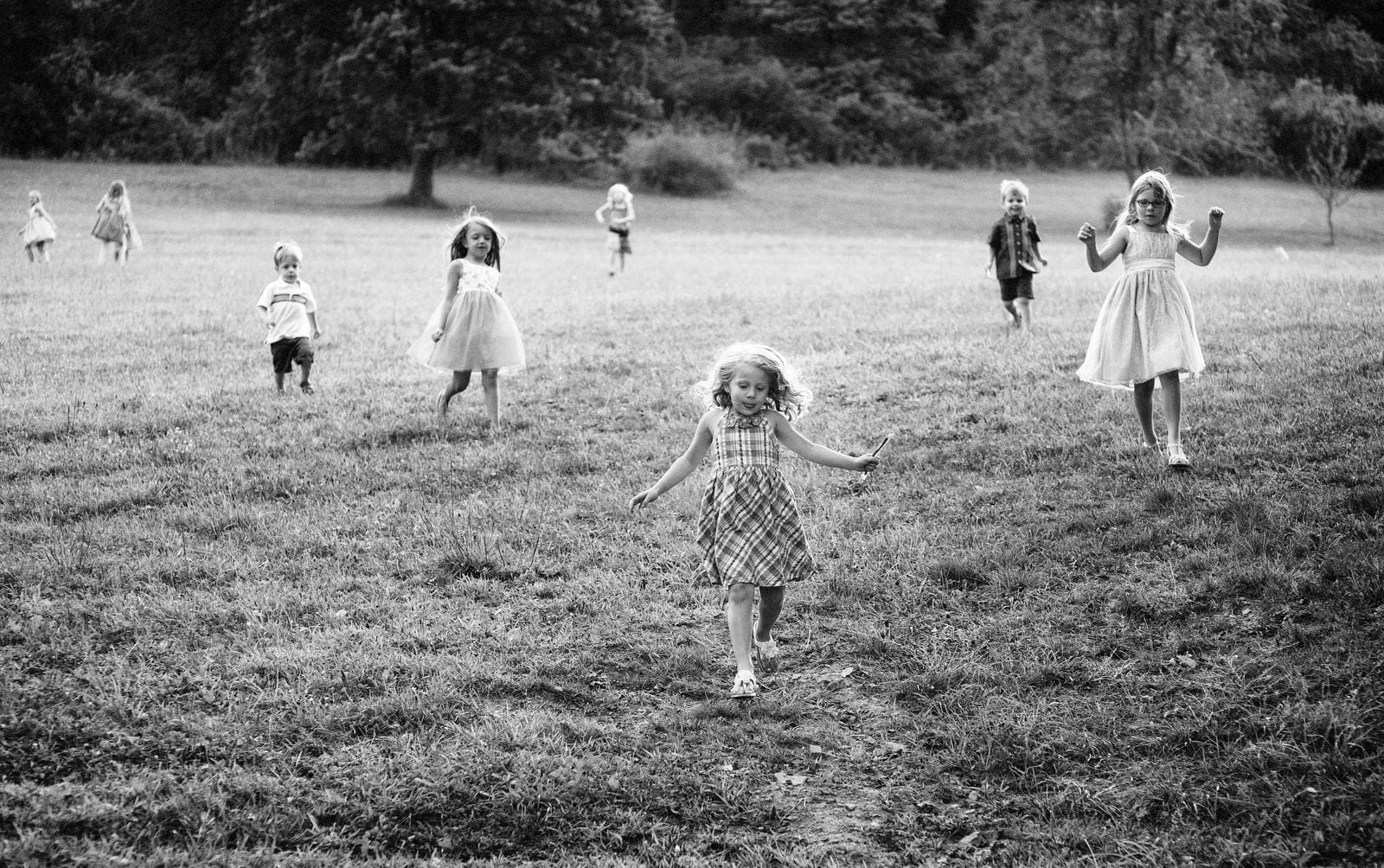 A group of children run down a grassy hill during a wedding at Chanteclaire Farm.