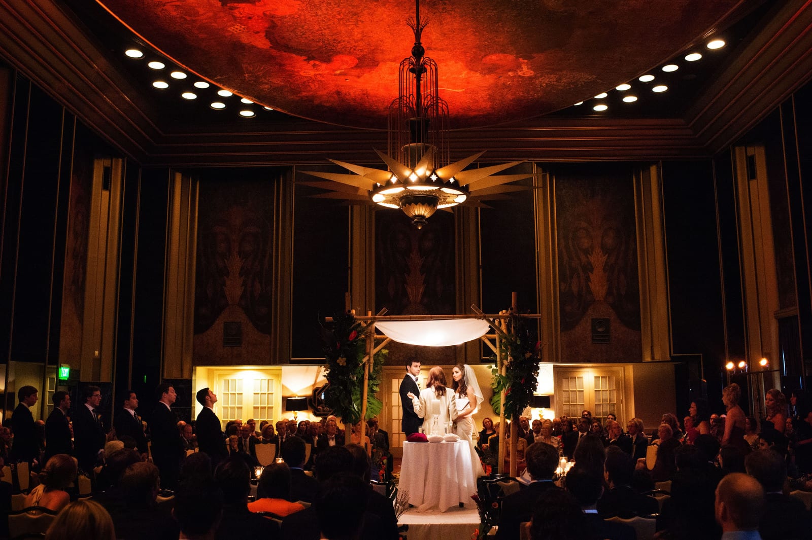 A bride and groom stand beneath a lighted chuppah in the art deco Urban Room at the Omni William Penn Hotel.