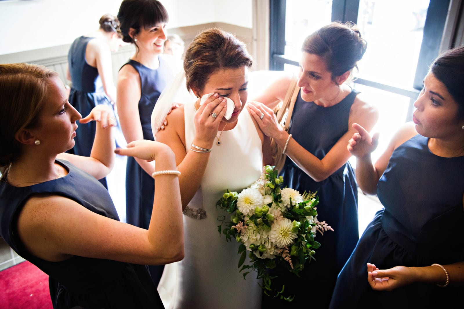 A bride wipes tears from her eyes as she is surrounded by bridesmaids before her wedding at St. Stanislaus church in the Strip District.