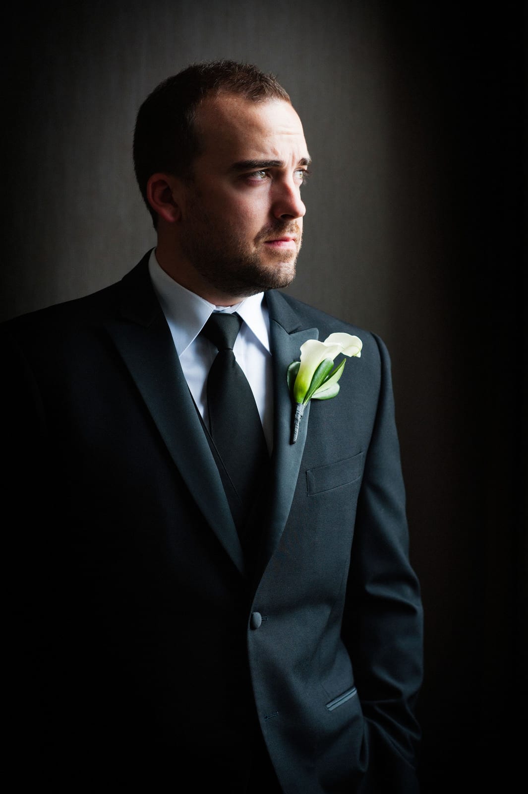 A groom looks to the right in a dramatic portrait before his wedding at the Renaissance Hotel Pittsburgh.