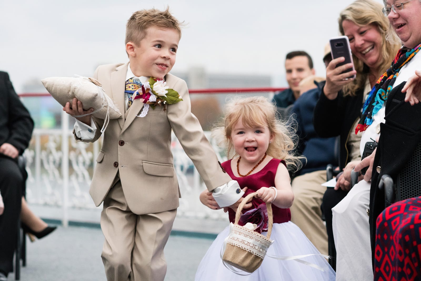 A grinning flower girl and ring bearer run down the aisle during a wedding on the Gateway Clipper.