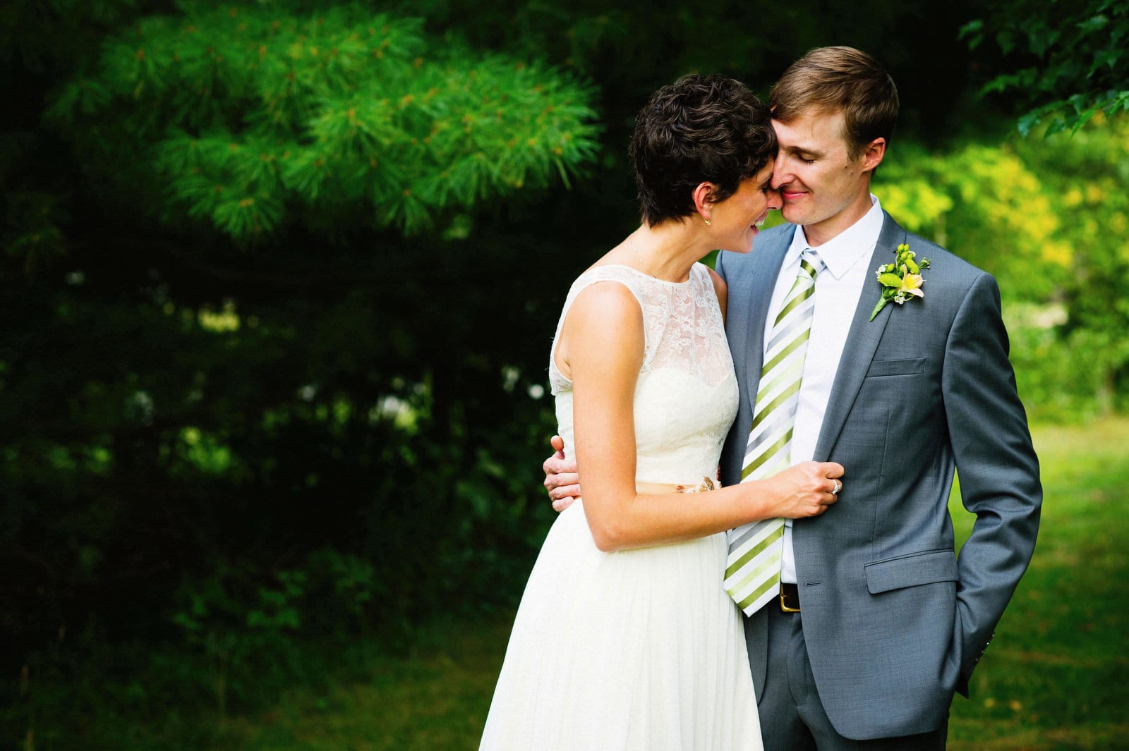 A bride and groom smile and embrace on a forest path after their wedding at the Succop Conservancy./