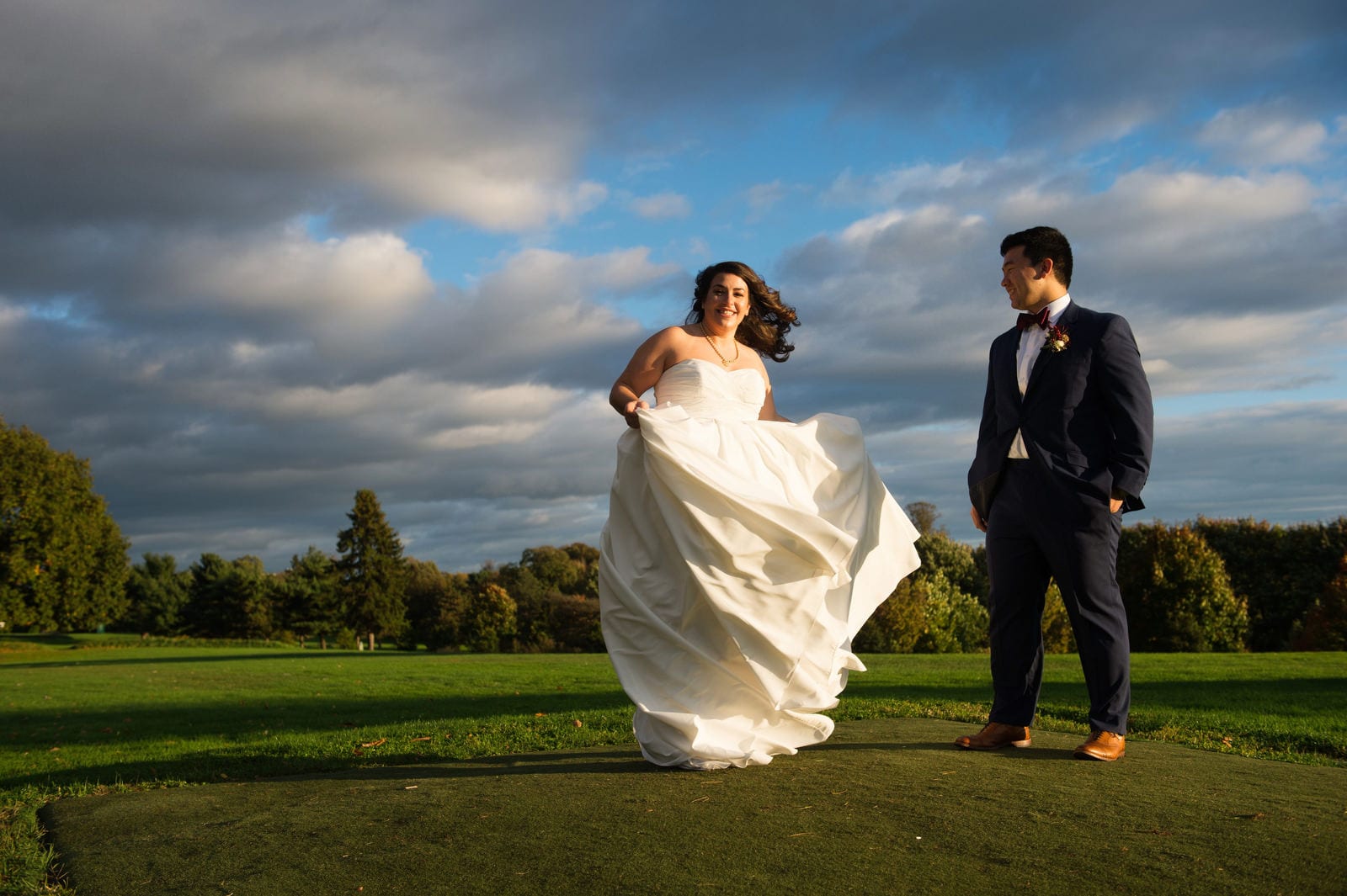 A bride and groom stand in the afternoon sunlight on the putting green outside of the Pittsburgh Golf Club before their wedding.