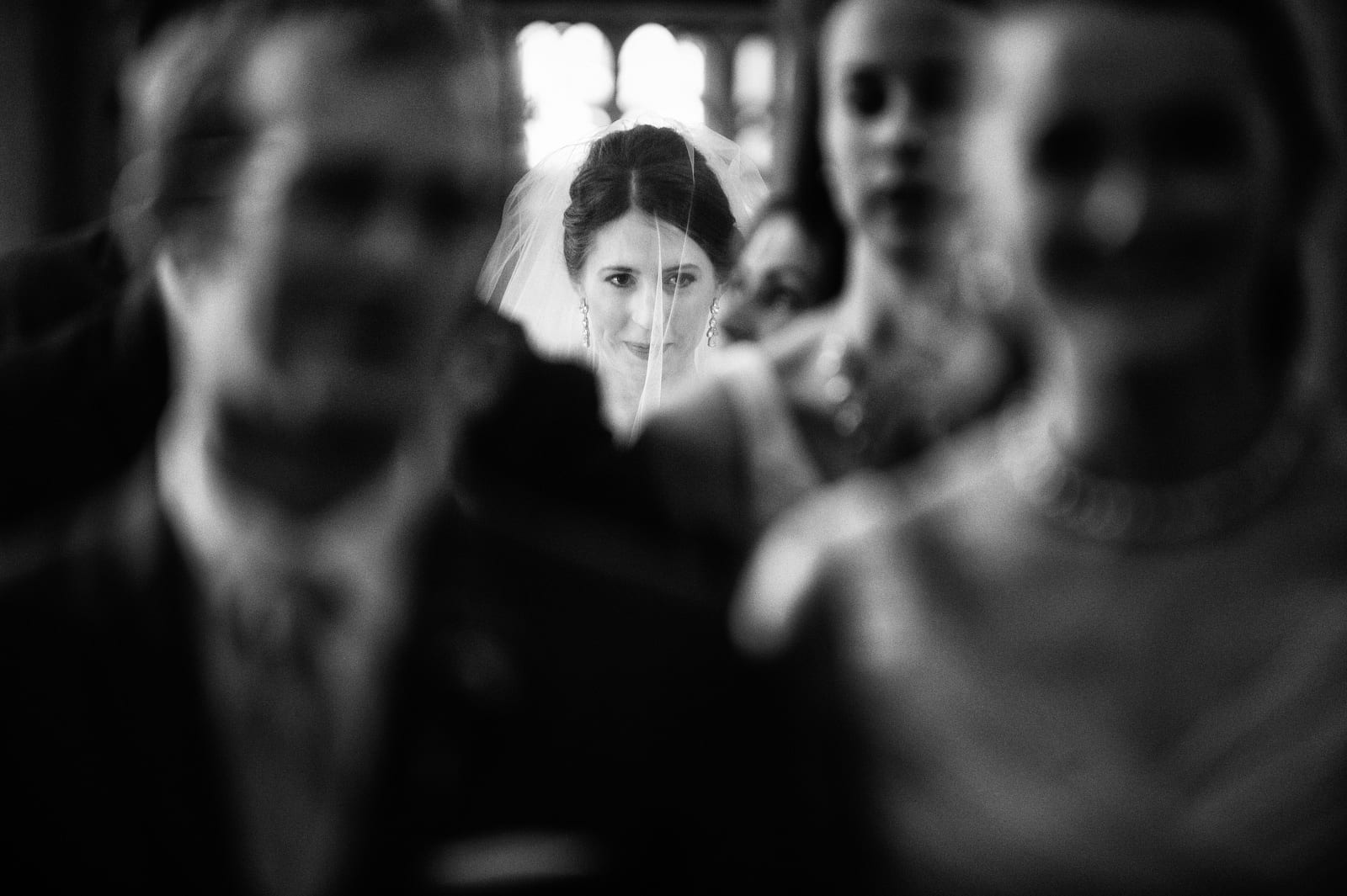 A bride looks forward in concentration as seen through the line of bridesmaids and groomsmen at her wedding at St. Paul Cathedral in Pittsburgh.