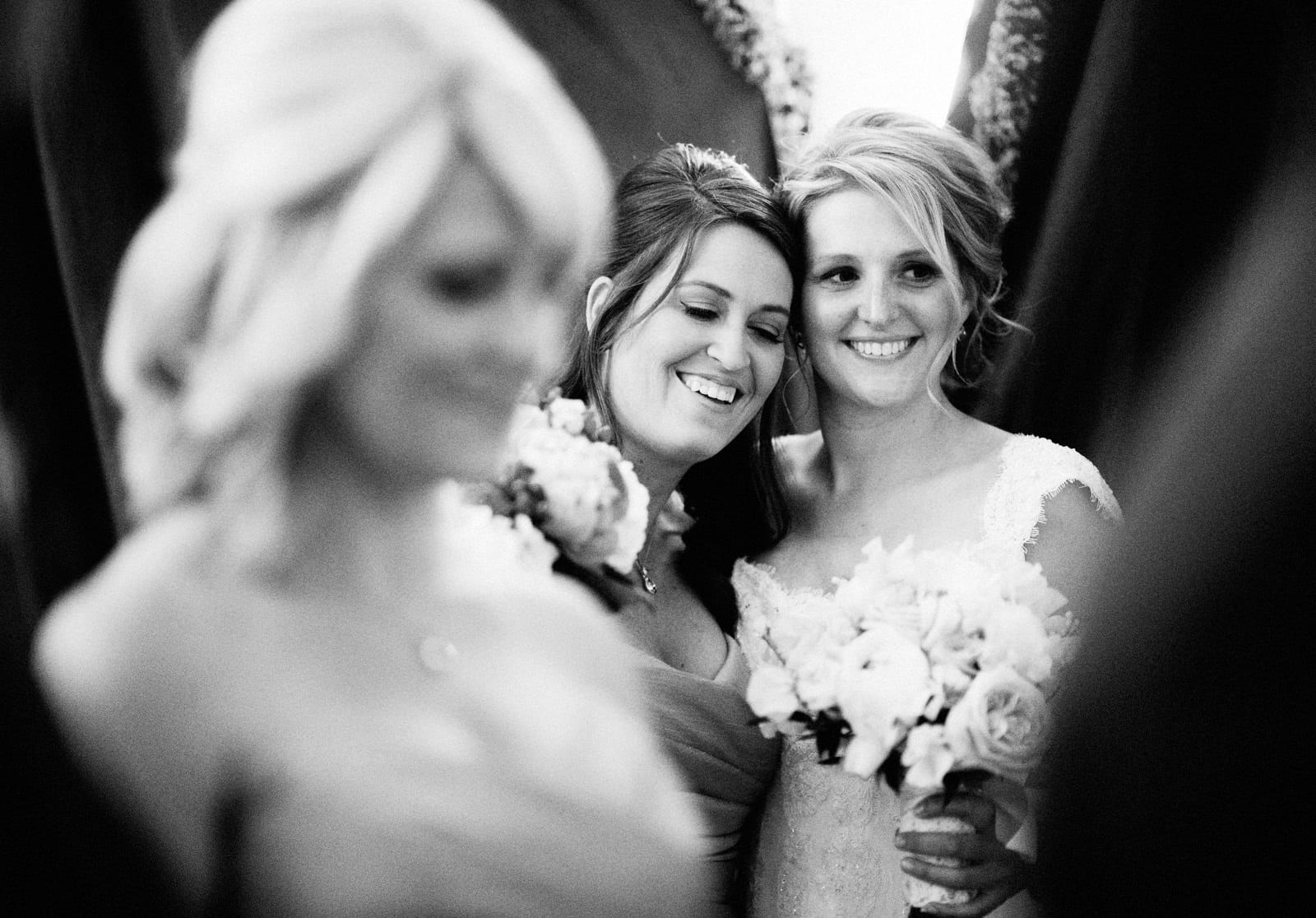 A smiling bride hugs her maid of honor while waiting for her wedding at the Fox Chapel Golf Club to begin.