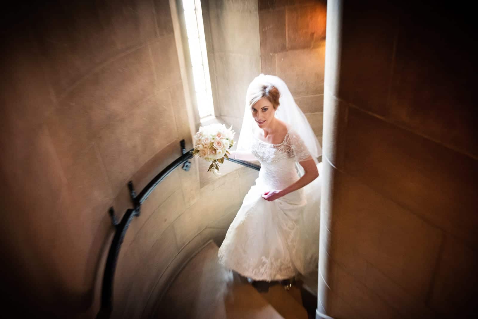 A bride holds her bouquet in her hand as she walks up the stairs before her wedding at Heinz Chapel.