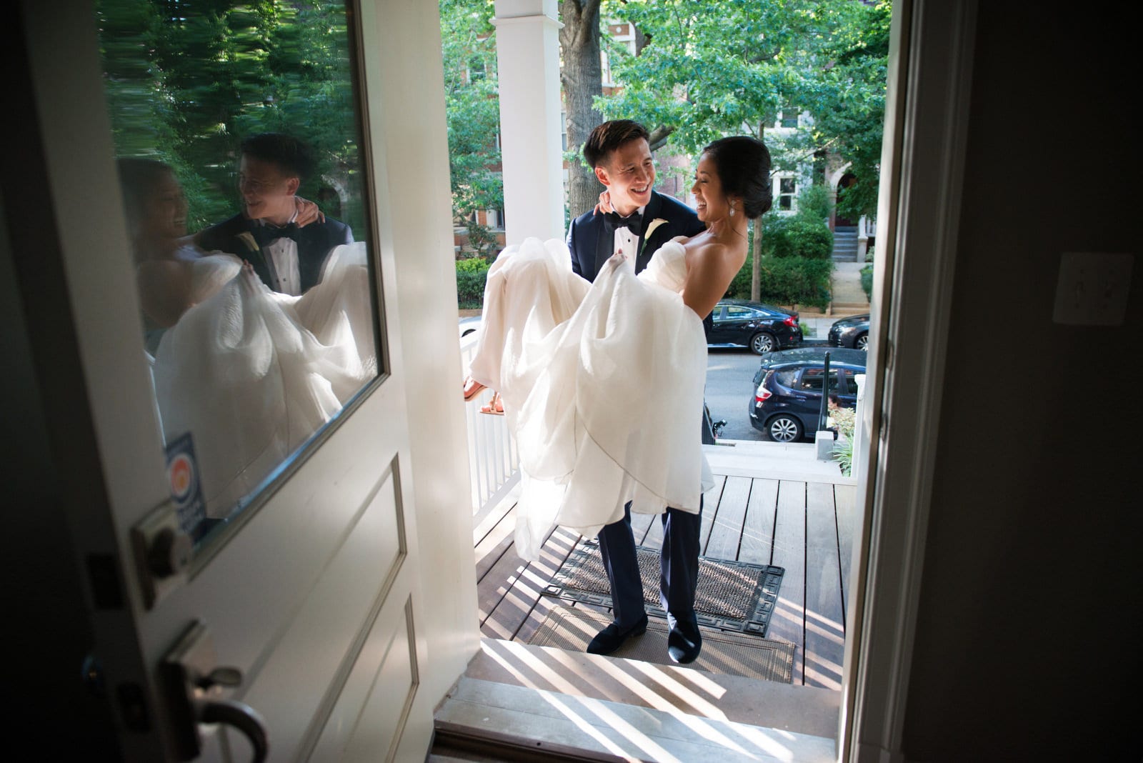 A groom carries his bride across the threshold of their home in the Kalorama neighborhood of Washington, DC.