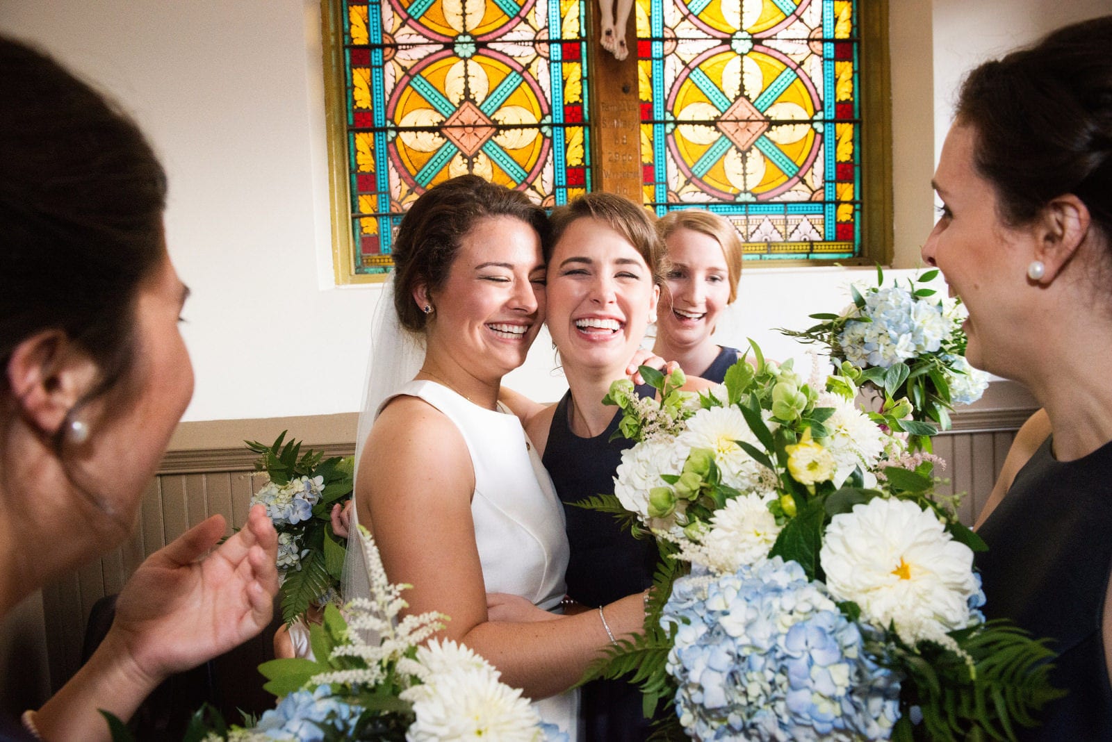 A smiling bride is hugged by her smiling bridesmaids after her wedding at St. Stanislaus church in the Strip District.