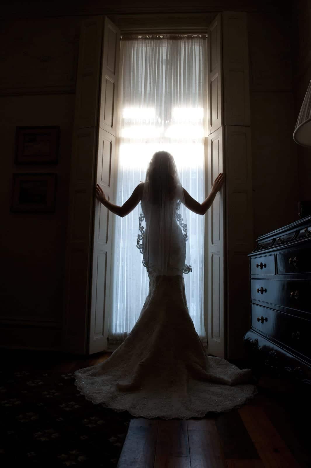 A bride stands in a floor to ceiling window at the Inn on Negley after her wedding.