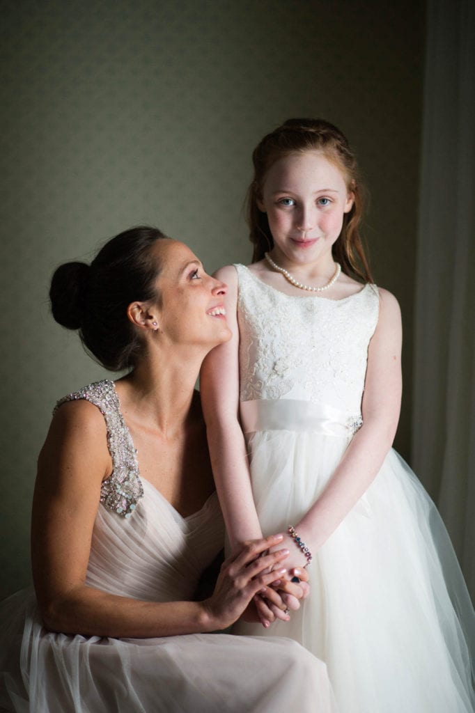 A bride in a dove grey dress sits and looks up at her daughter who is standing next to her before her Omni Bedford Springs wedding.