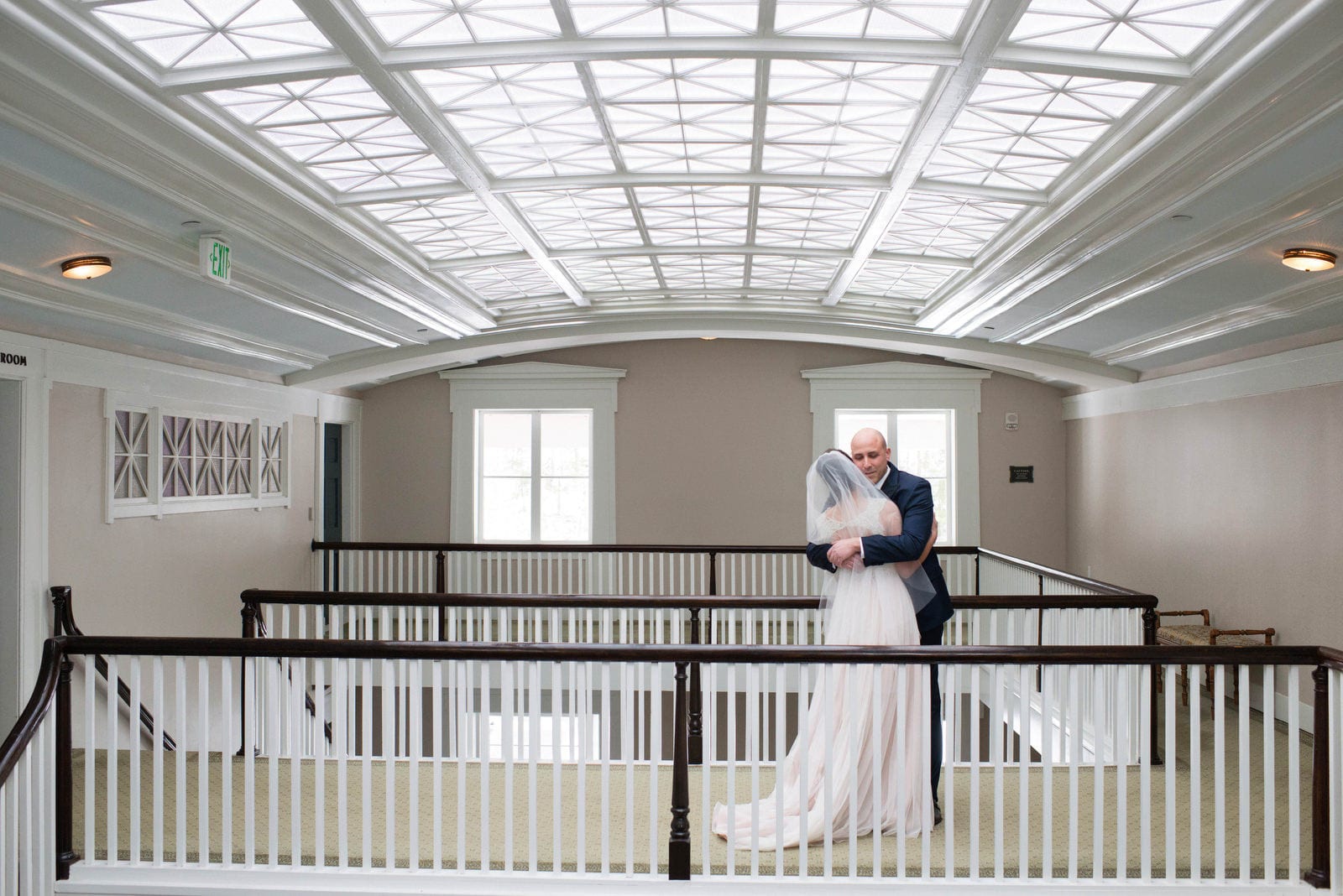 A groom embraces his bride beneath the skylight at the Omni Bedford Springs resort at the first look before their wedding.