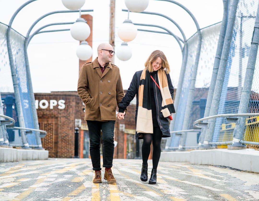 A couple holds hands as they walk across the blue pedestrian bridge between East Liberty and Shadyside in Pittsburgh.