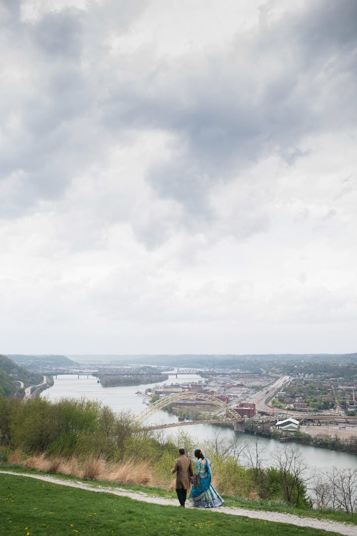 A couple walks along a path in Emerald View Park on Mt. Washington with the Ohio River and West End Bridge below them.