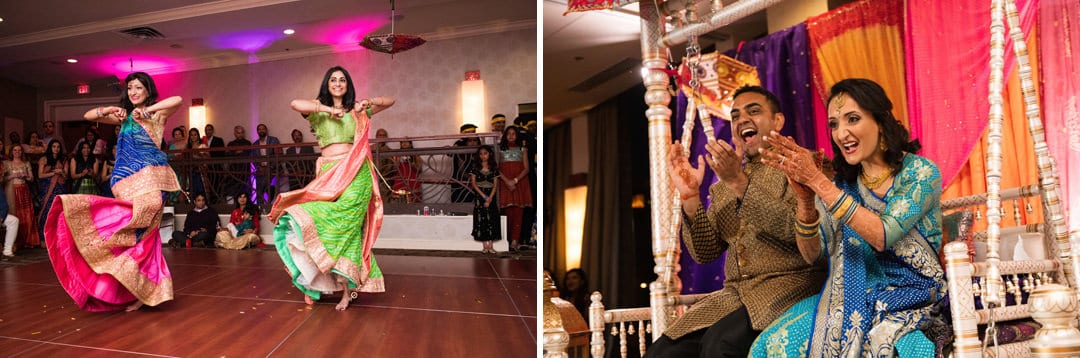 A pair of colorfully dressed young Indian women dance as a bride and groom sit on an ornate swing and applaud during their sangeet at the Wyndham Grand Pittsburgh.