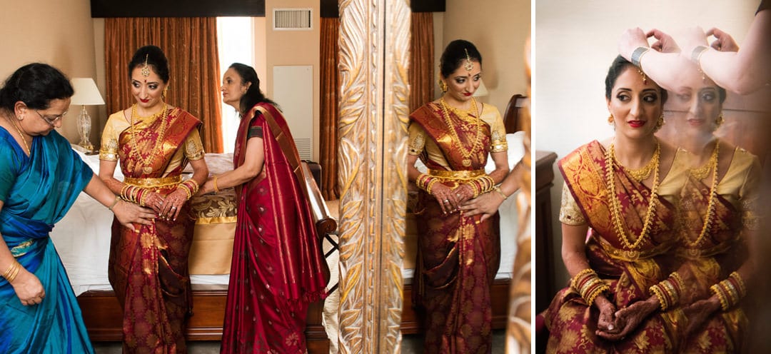 A bride is helped by two older Indian women as she gets her gold and red sari on before her Indian Wedding Pittsburgh Wyndham.