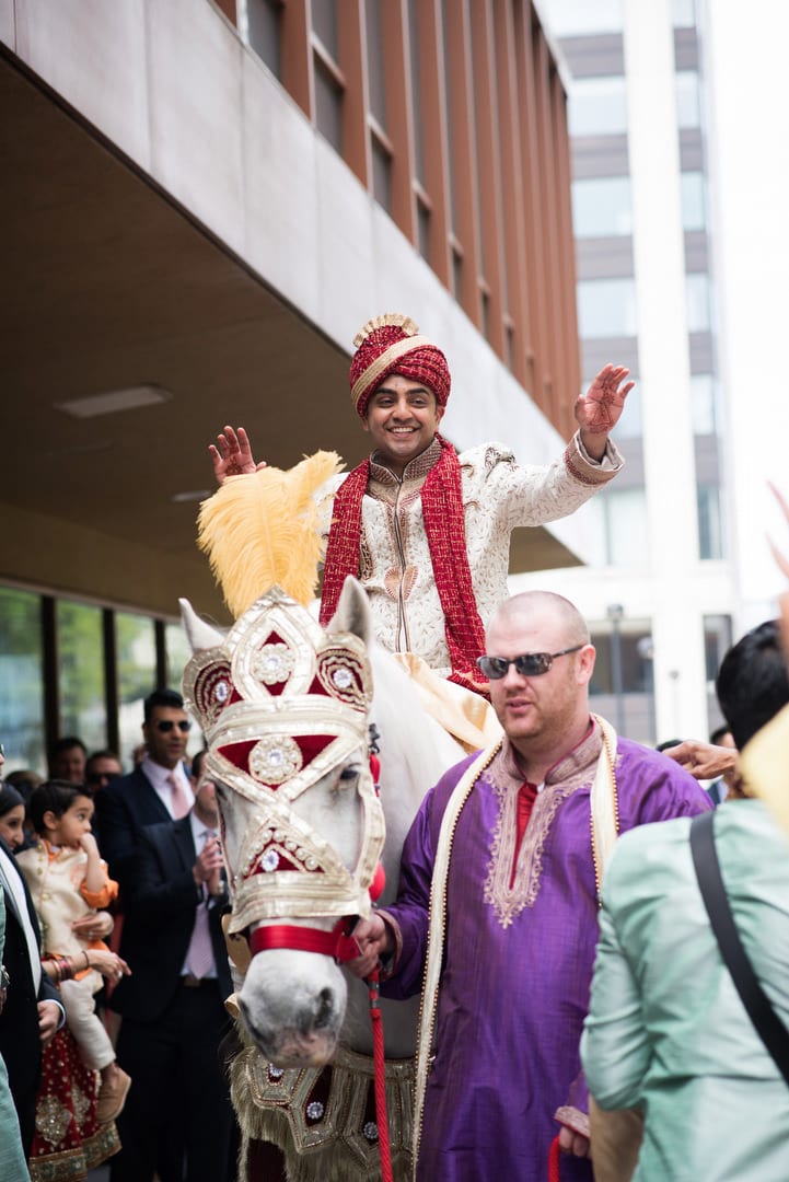 An Indian groom holds his hands out as he arrives to his baraat during his Indian Wedding Pittsburgh Wyndham.
