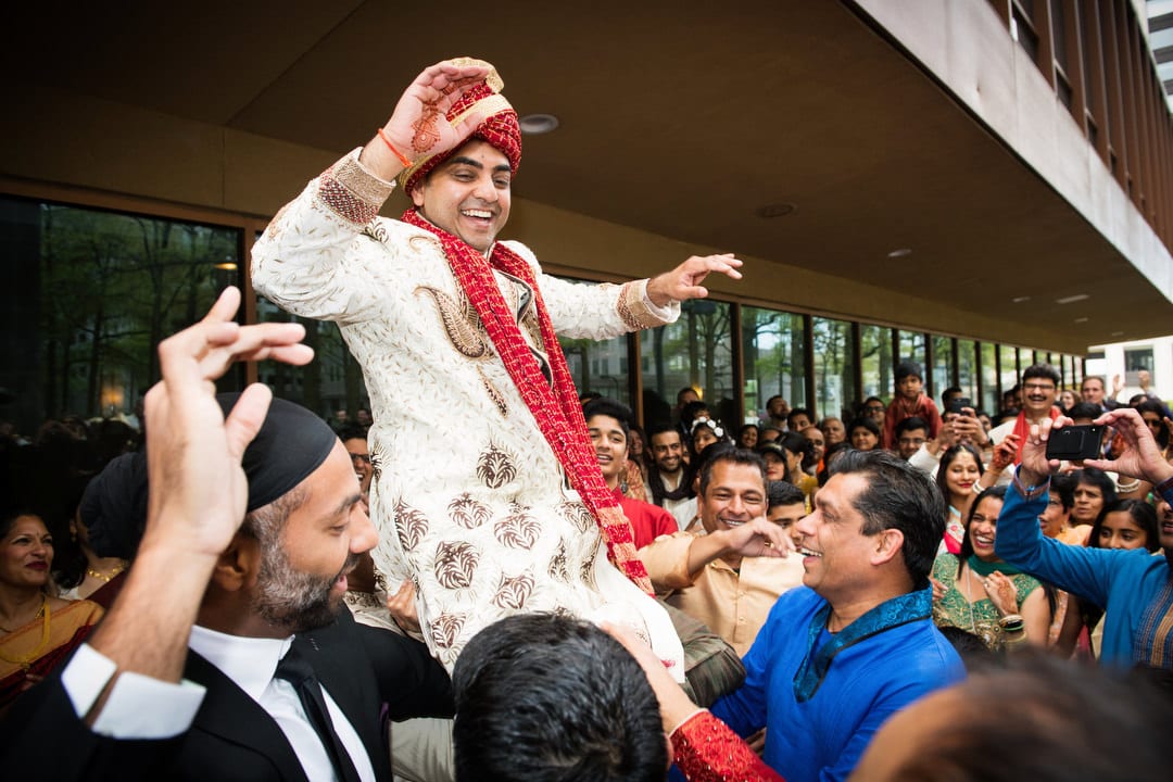 An Indian groom is lifted on the shoulders of his friends during his Baraat.