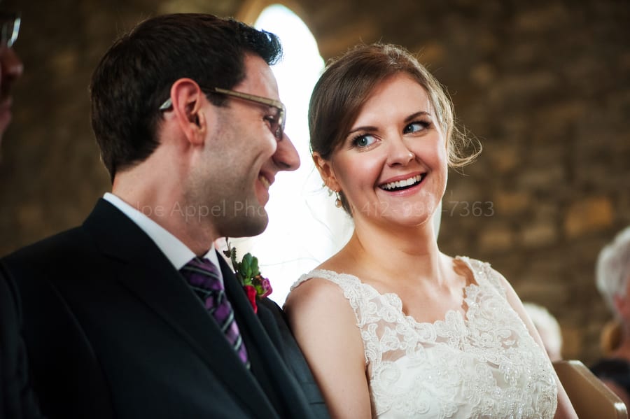 Bride and groom smile while looking at each other at the front of the church before their wedding. Old St. Luke's Church Wedding